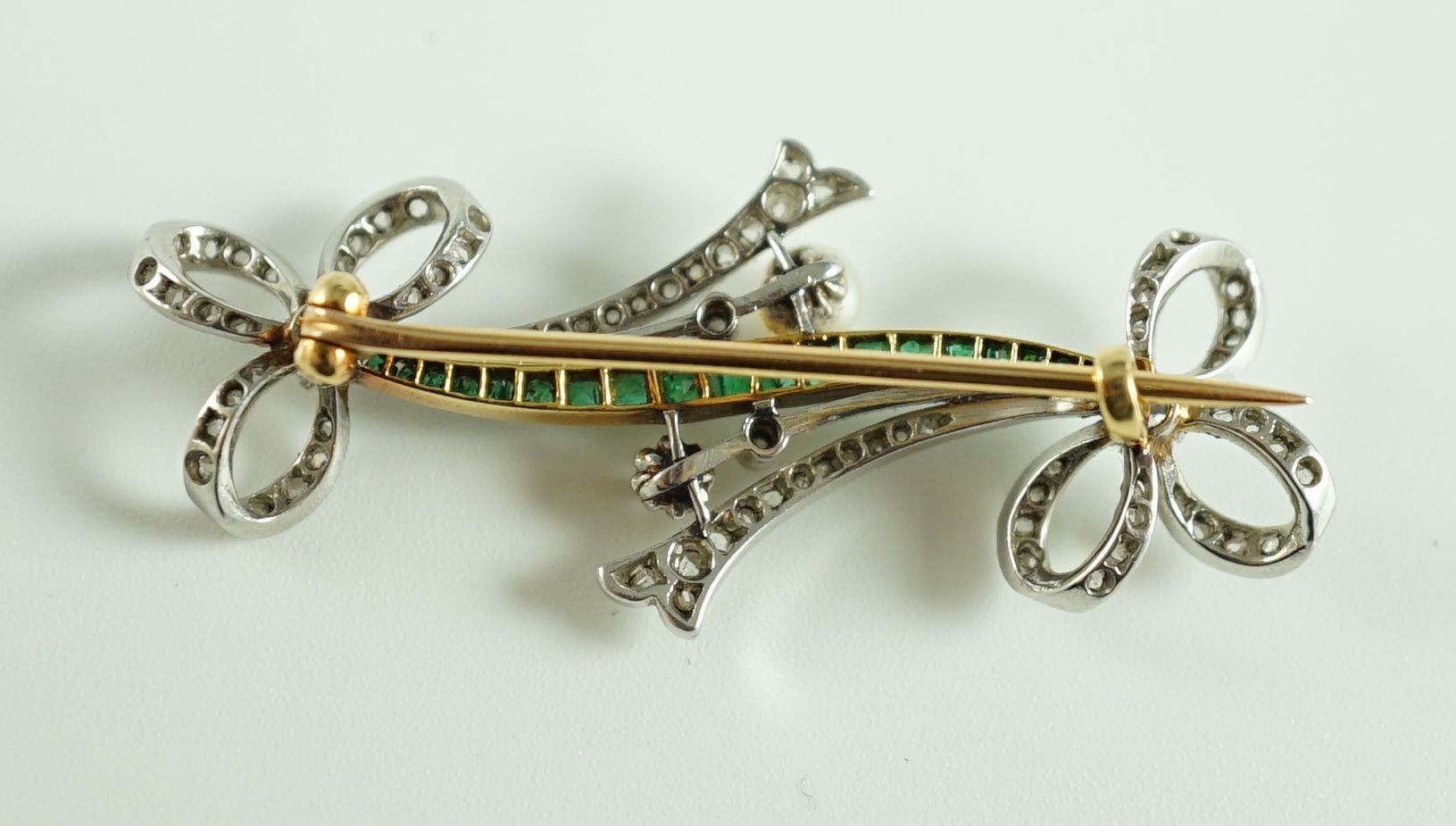 A Belle Epoque gold and platinum, emerald, diamond and seed pearl set twin ribbon bow bar brooch